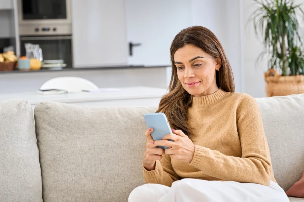 Woman sitting on couch, reading on her phone